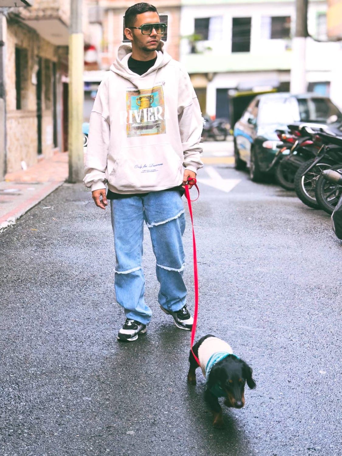 Daniel paseando a un perro salchicha con la correa suelta por una calle de Medellín