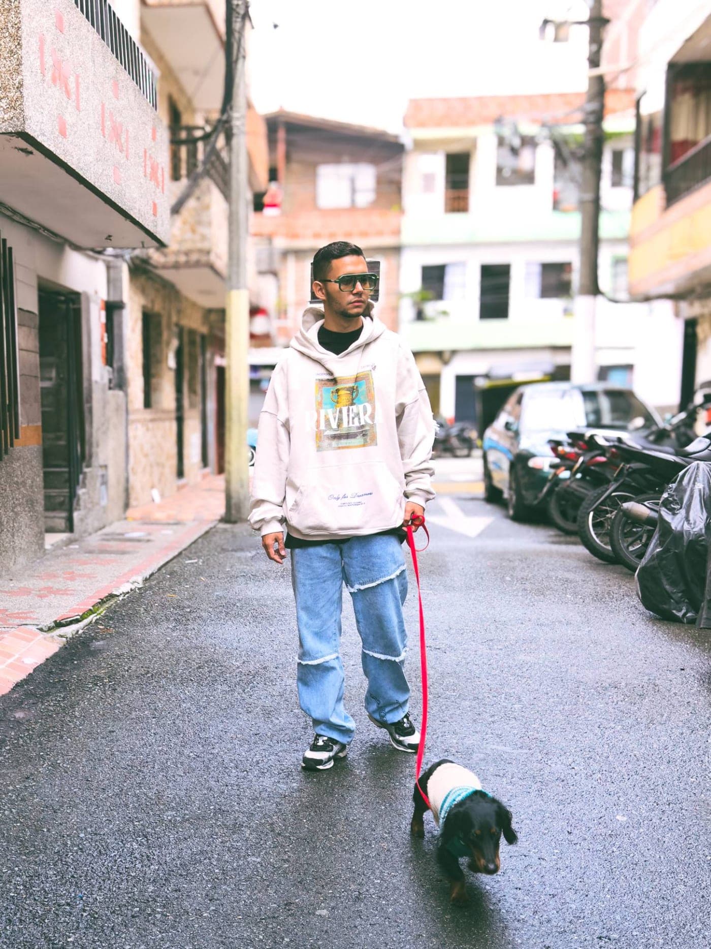 Daniel Londoño, adiestrador canino, paseando a un perro salchicha por una calle de Medellín
